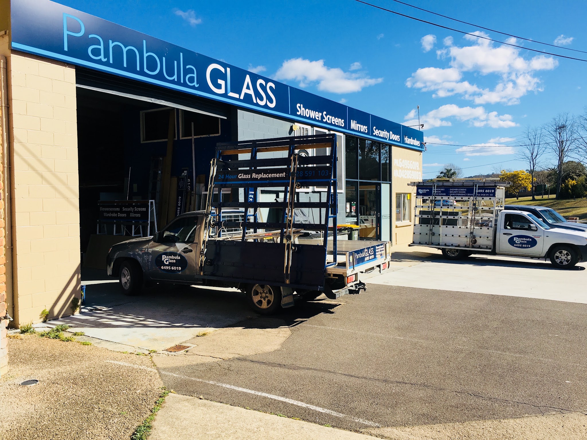 The Pambula Glass shopfront on Arthur Kaine Drive with two liveried work utes out the front