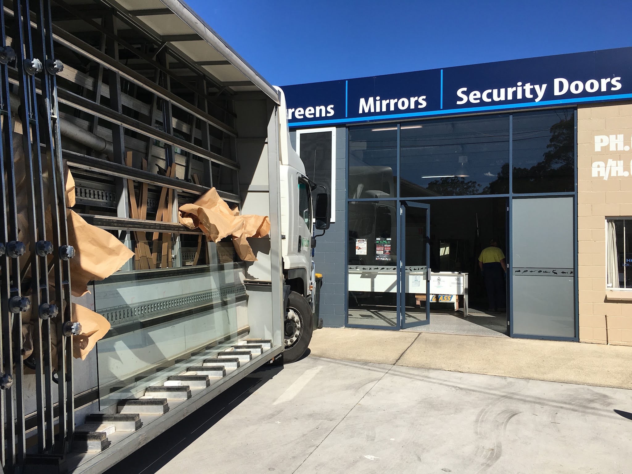 A glass delivery truck unloading racked sheets at the Pambula Glass roller door
