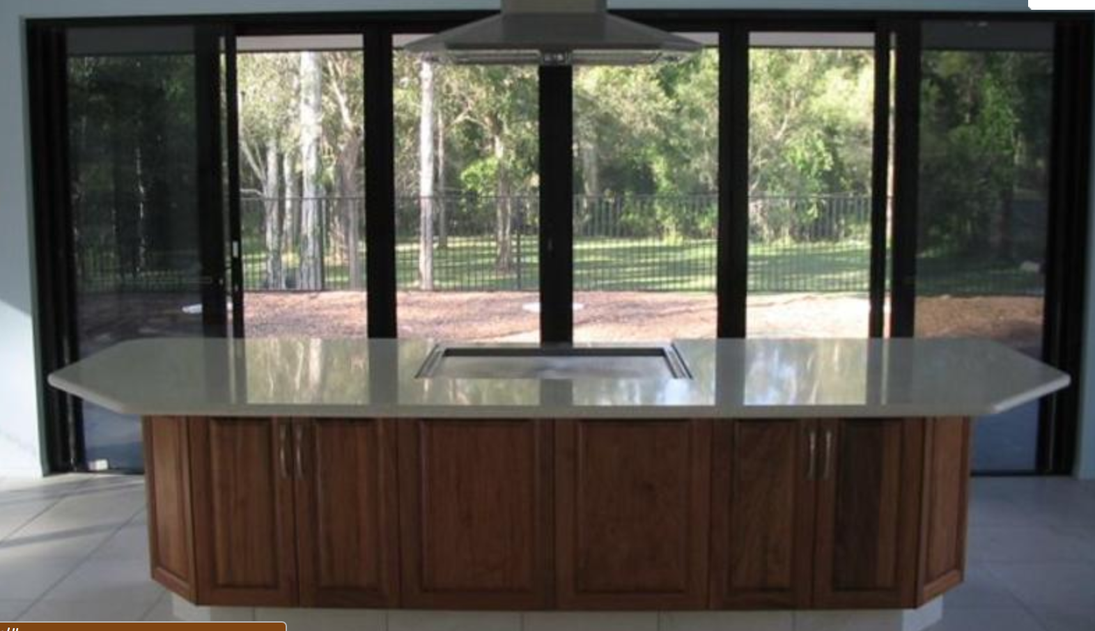 Black framed stacking glass doors in a kitchen, opening onto bushland